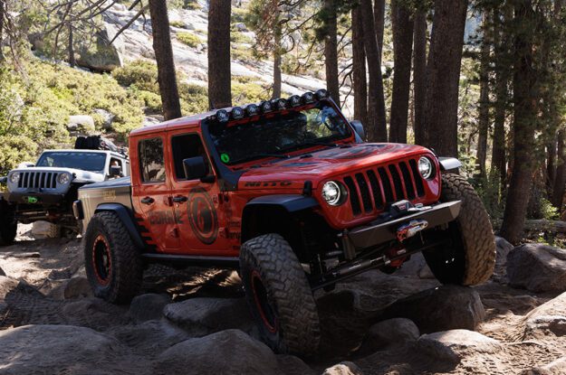Red Jeep Gladiator climbing rocks with a Jeep following.