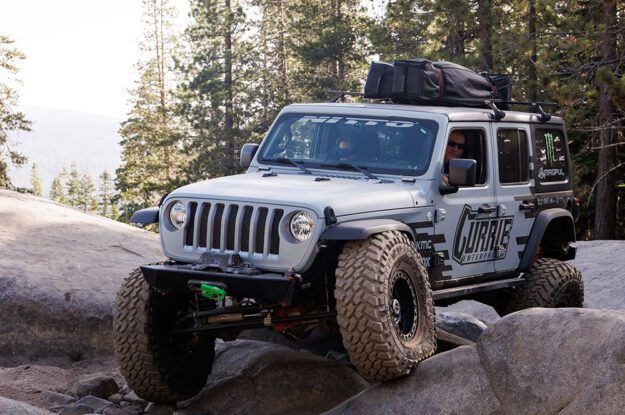 Jeep with tire on rock hitting fender.