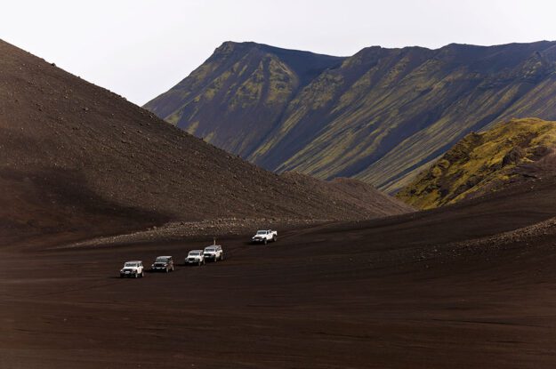 row of jeeps in black sand