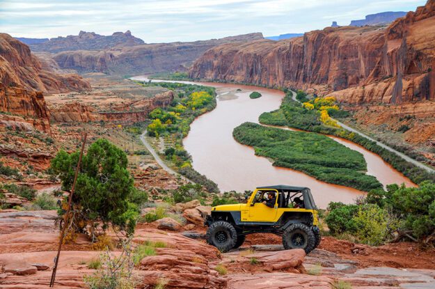 Yellow Jeep above a scenic river view.