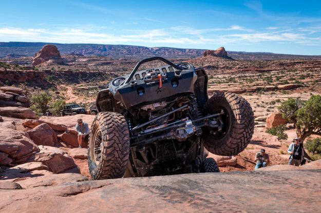 Jeep climbing rock with wheel in the air.