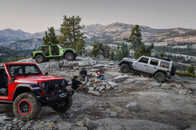 Three poeple and their Jeeps around a campfire.