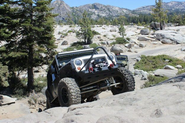 Jeep climbing up steep rock face.