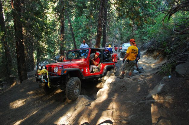 Trail guides watch as Jeeper drives through rocks.