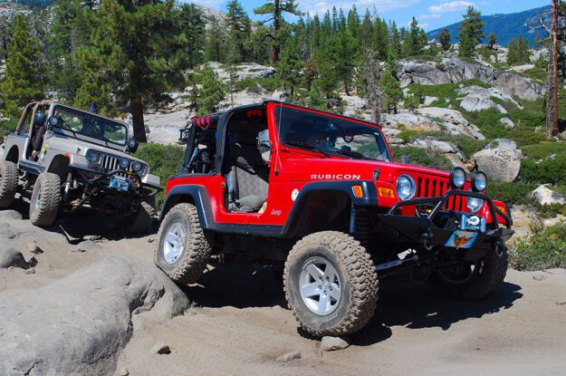 Two Jeeps on the Rubicon Trail with trees in the background.
