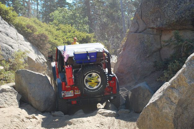 Red Jeep navigating rocky section.