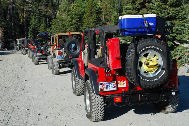 A line of jeeps on a gravel road.