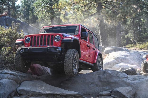 Red Jeep driving over rocks.