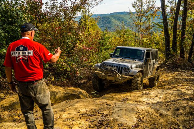 Trail guide guiding jeeper up rocks