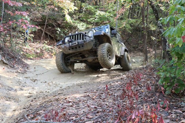 Jeep in mud with one wheel off the ground