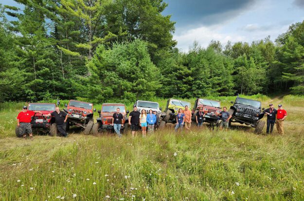Jeeps parked on each others front tire with people