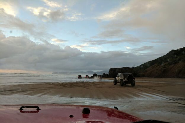 Jeeps driving thhrough water on sand