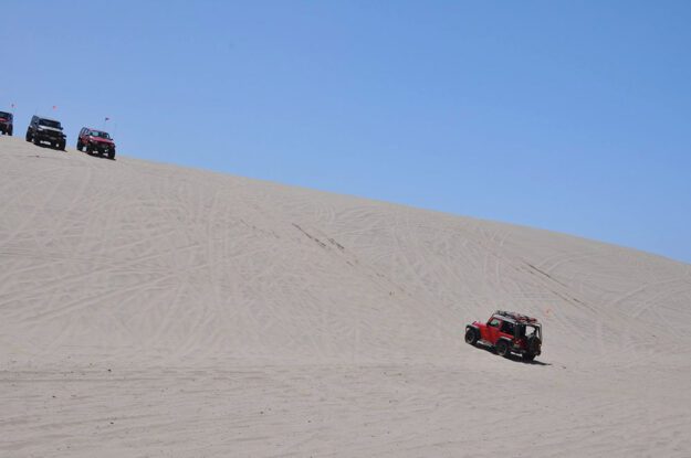 Jeep driving up sand hill